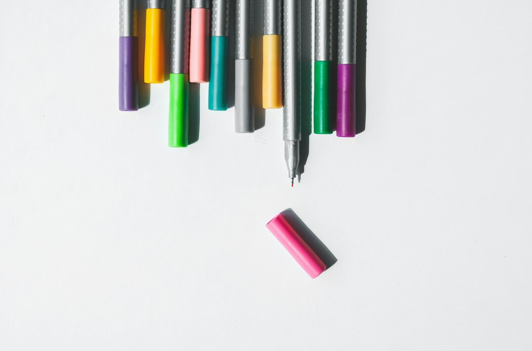 Flat lay of survey questionnaires, colored pens and a laptop with a bar chart